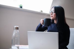 An online student enjoys a hot drink while studying her online degree.